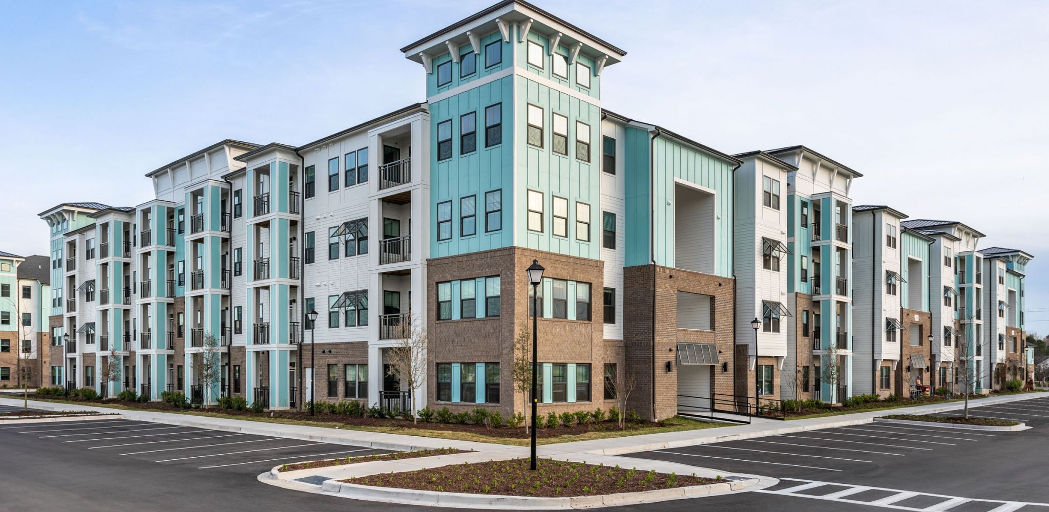 Hawthorne at The Milllarge teal and white apartment building with brick foundation.