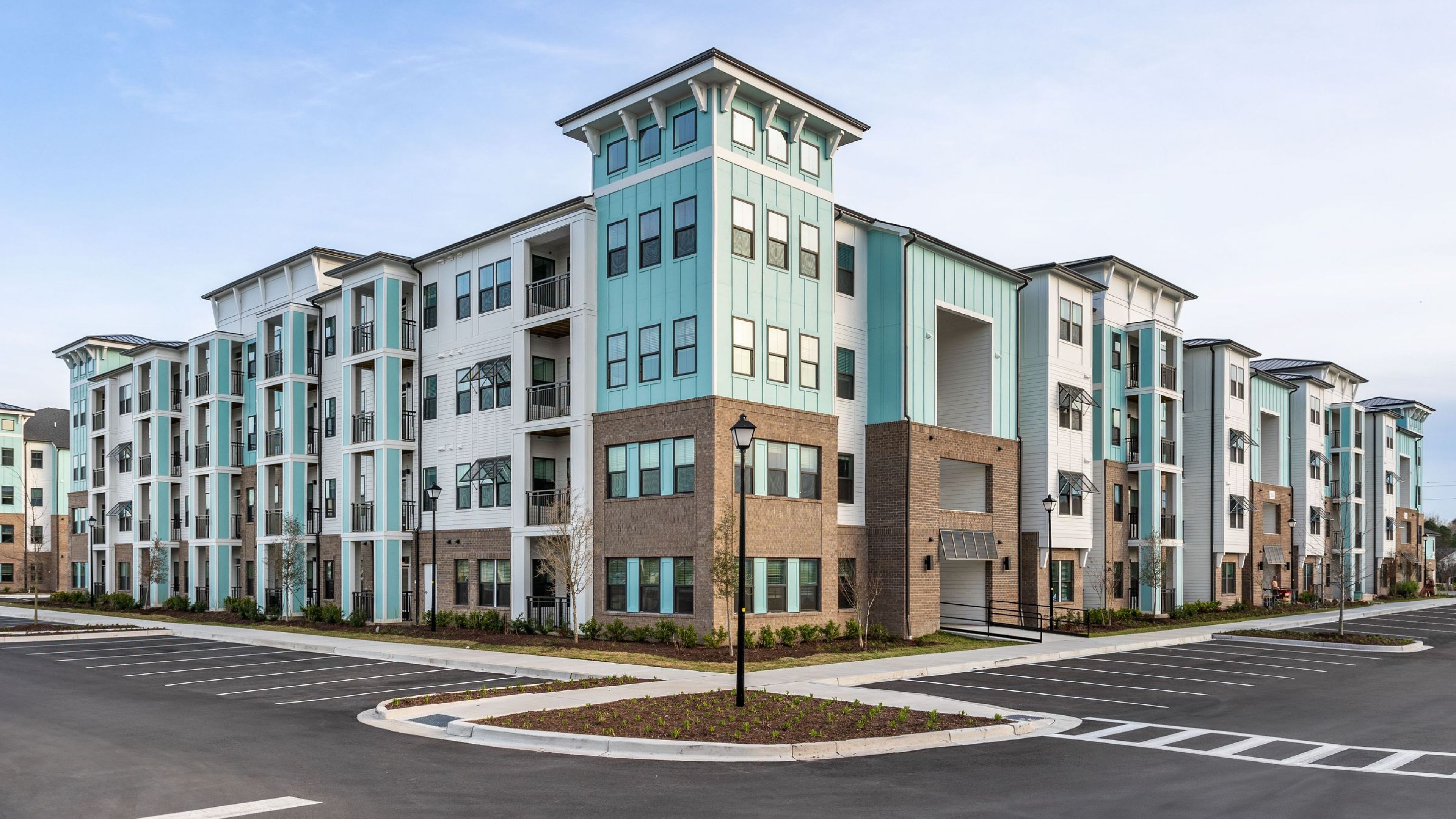 Hawthorne at the Mill large teal and white apartment building with brick foundation.